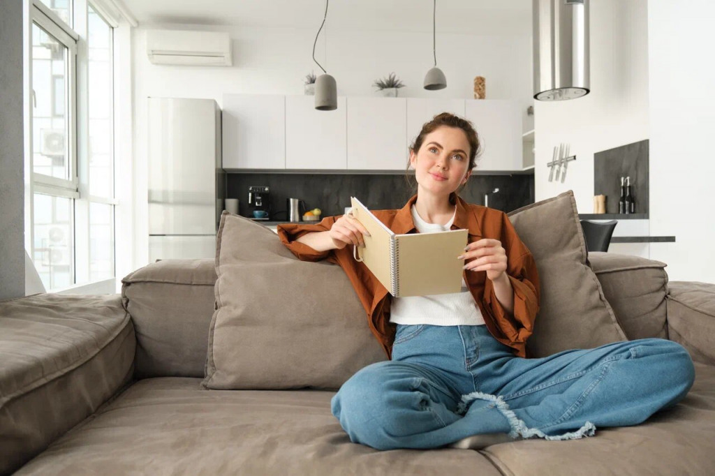 young-woman-using-phone-while-sitting-sofa-home.jpg